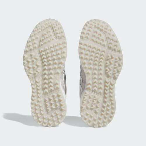 Pair of white sneaker outsoles with textured pattern.